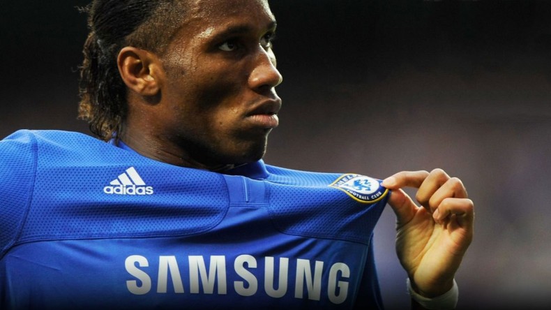 Didier Drogba holding Chelsea's badge on his jersey